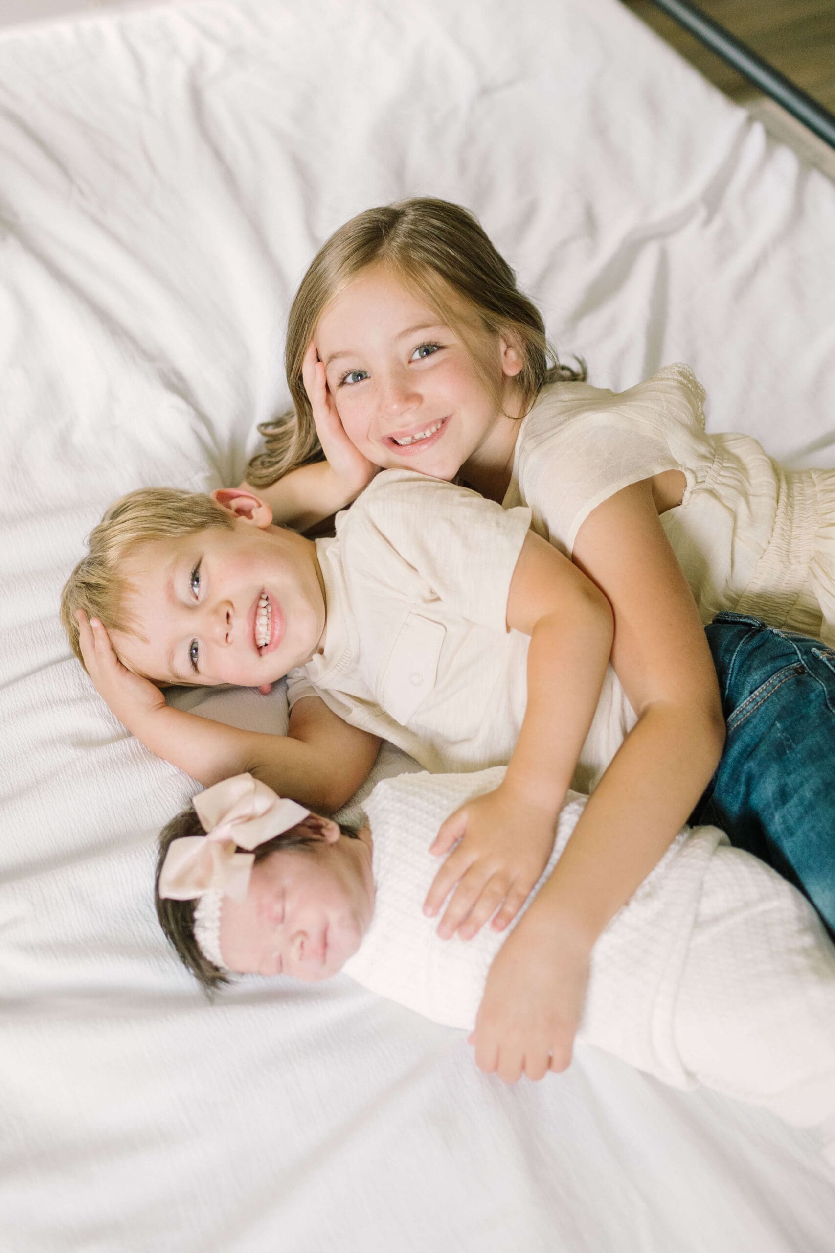 two siblings lay with their newborn baby sister after she is born with the help of raleigh doulas