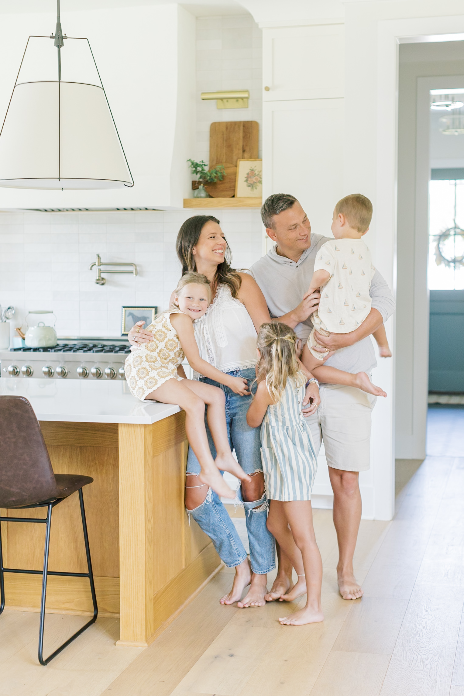 a happy family of 5 with toddlers laugh in a modern kitchen