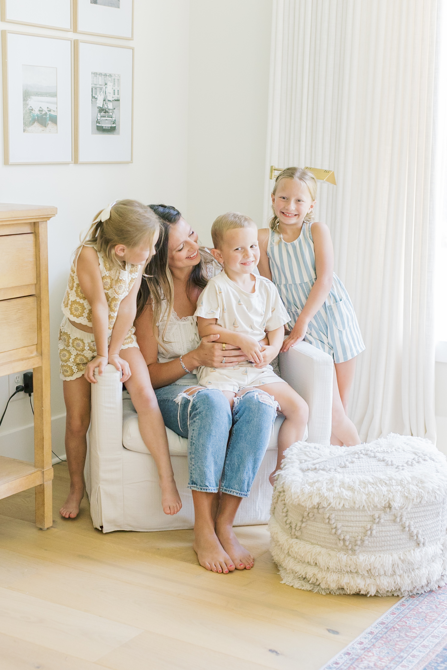 A happy mom sits in a chair with her toddler son in her lap and young daughters laughing on either side after some parenting classes in raleigh nc