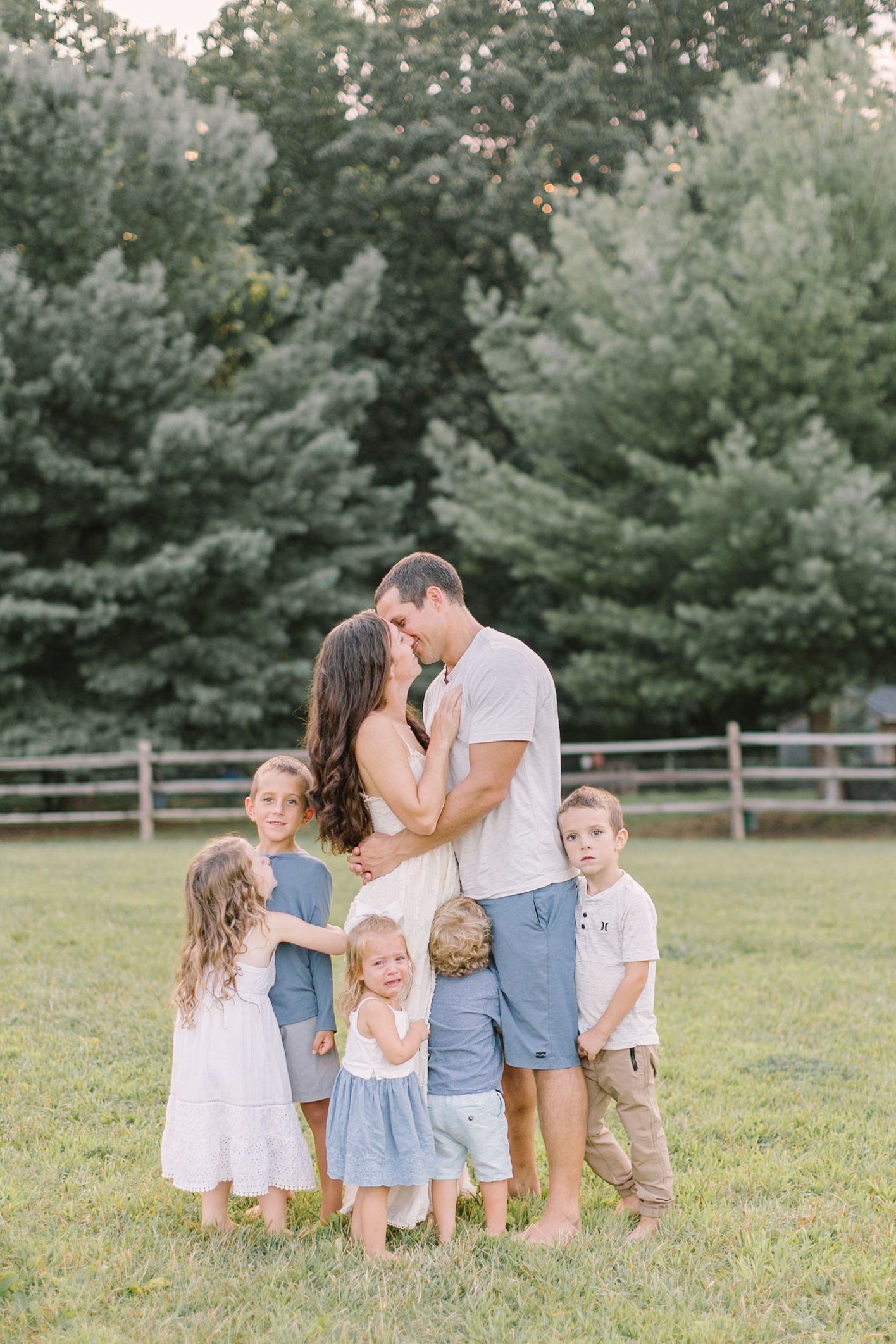 Mom and dad kiss while their five young children hug them, smile and cry after visiting children's boutiques in Raleigh, NC