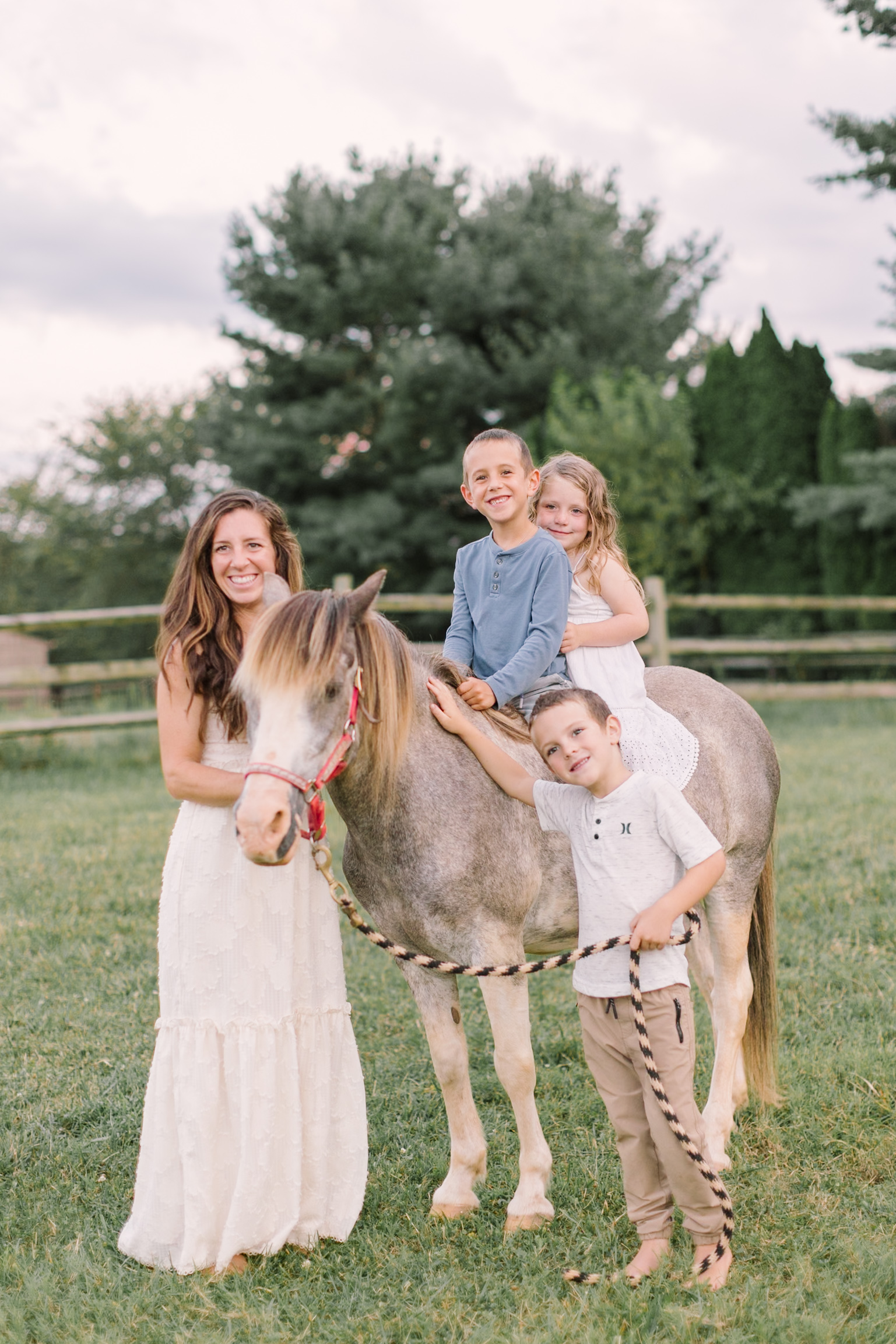 A mom walks a pony with her two toddler children sitting on it and one holding the lead after visiting children's boutiques in Raleigh, NC
