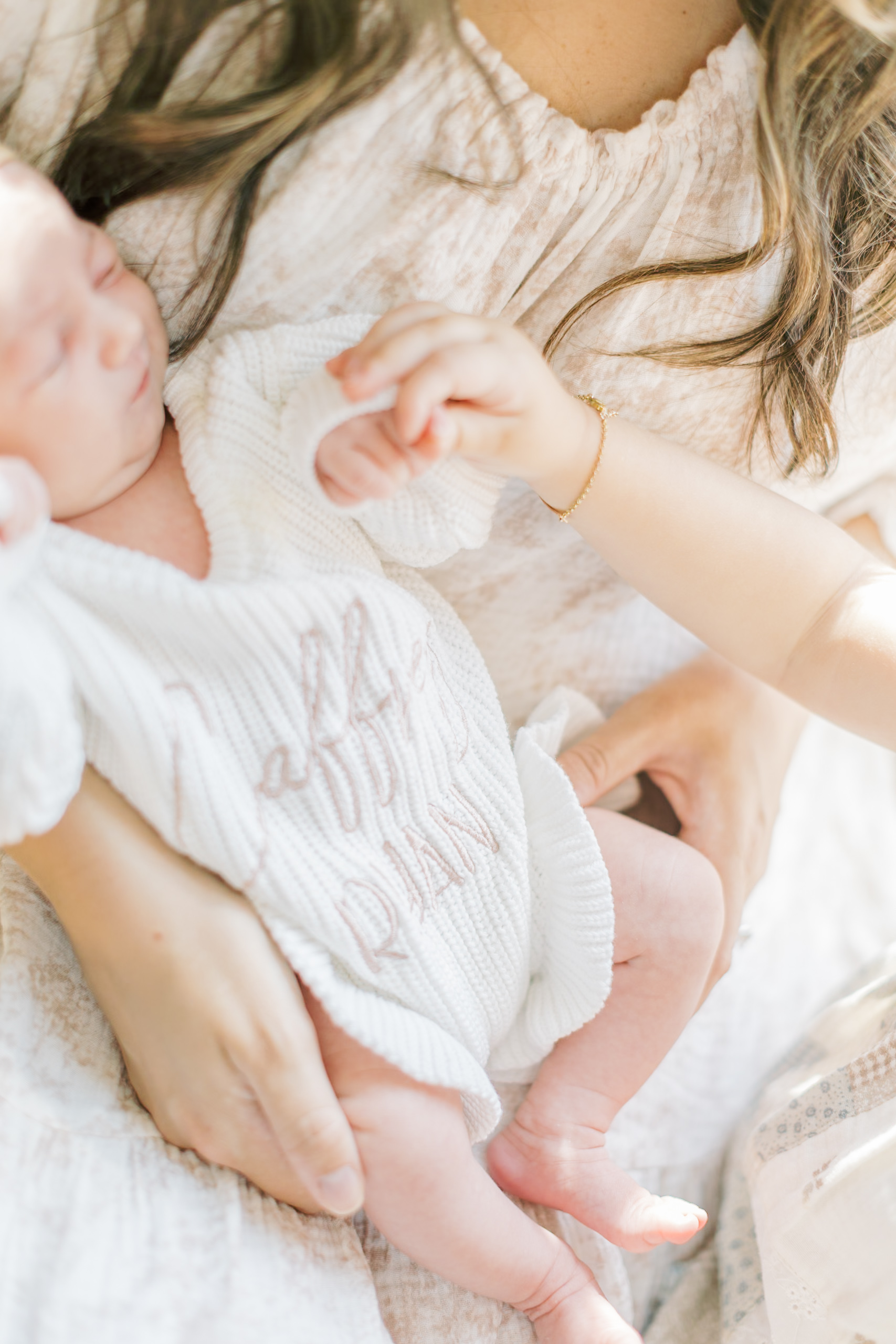Details of a custom onesie on a newborn in mom's lap