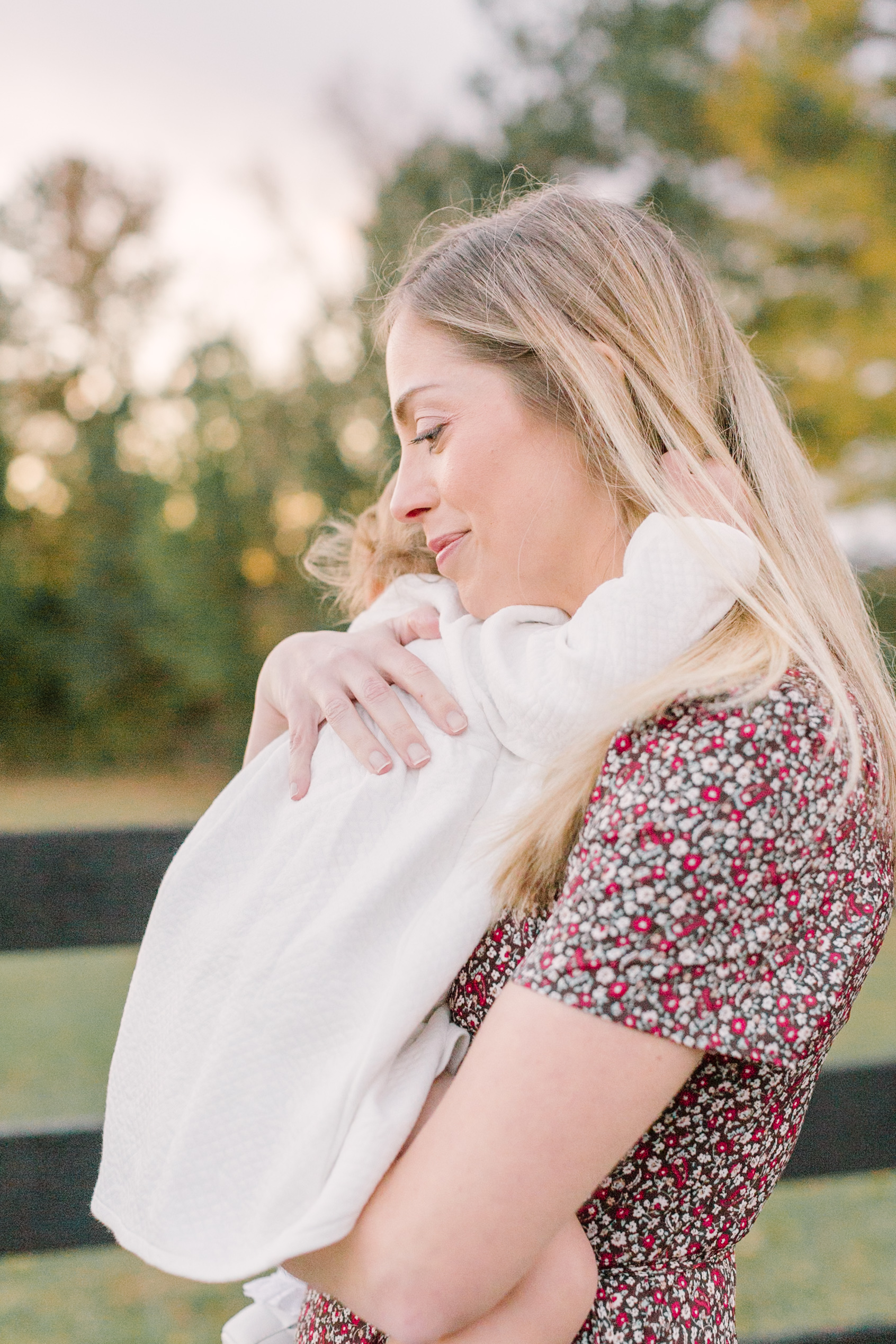 A happy mother hugs her toddler in a field at sunset before exploring easter sunrise services in Raleigh, NC