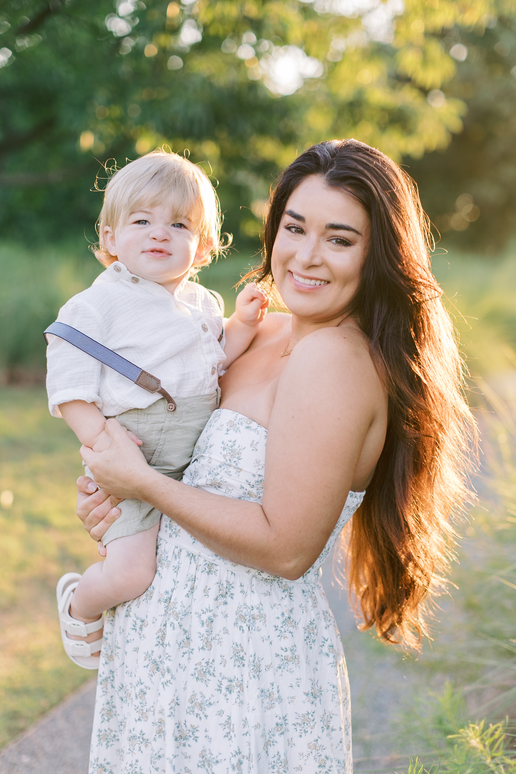 A happy mother stands while holding her young son in a park after the attend baby music classes in raleigh nc.