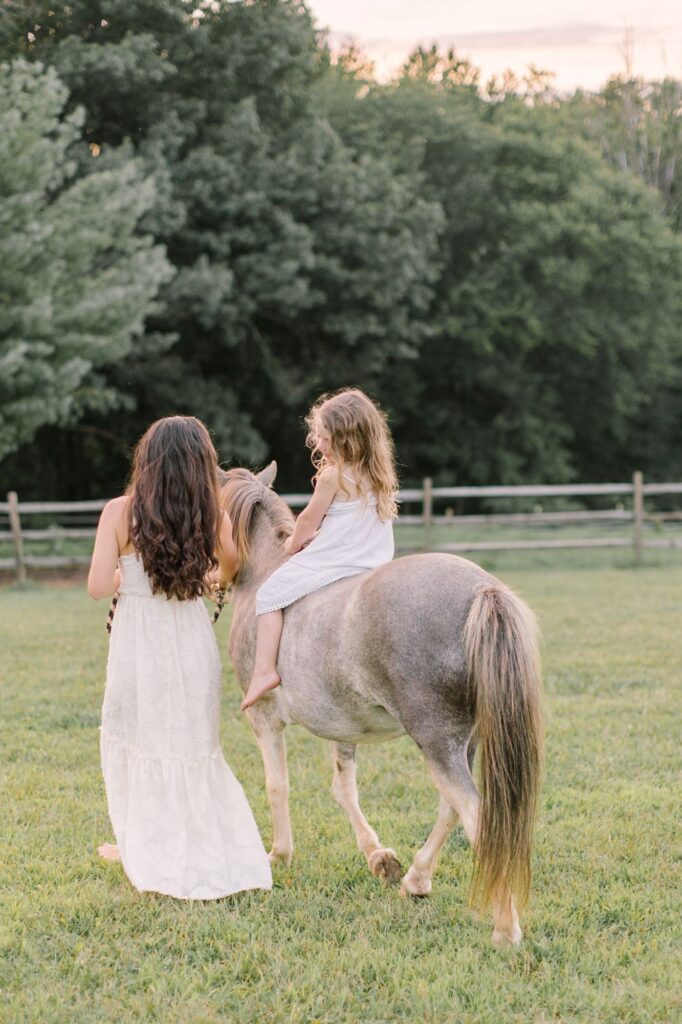 Mother and daughter walking with a pony during a family session, showing how planning meaningful activities can help families prepare for a photoshoot.