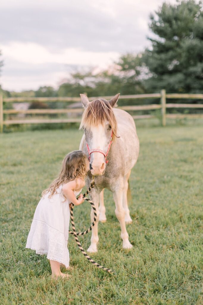 Young girl interacting with a pony during a family session, a great example of how to prepare for a photoshoot by incorporating familiar experiences.