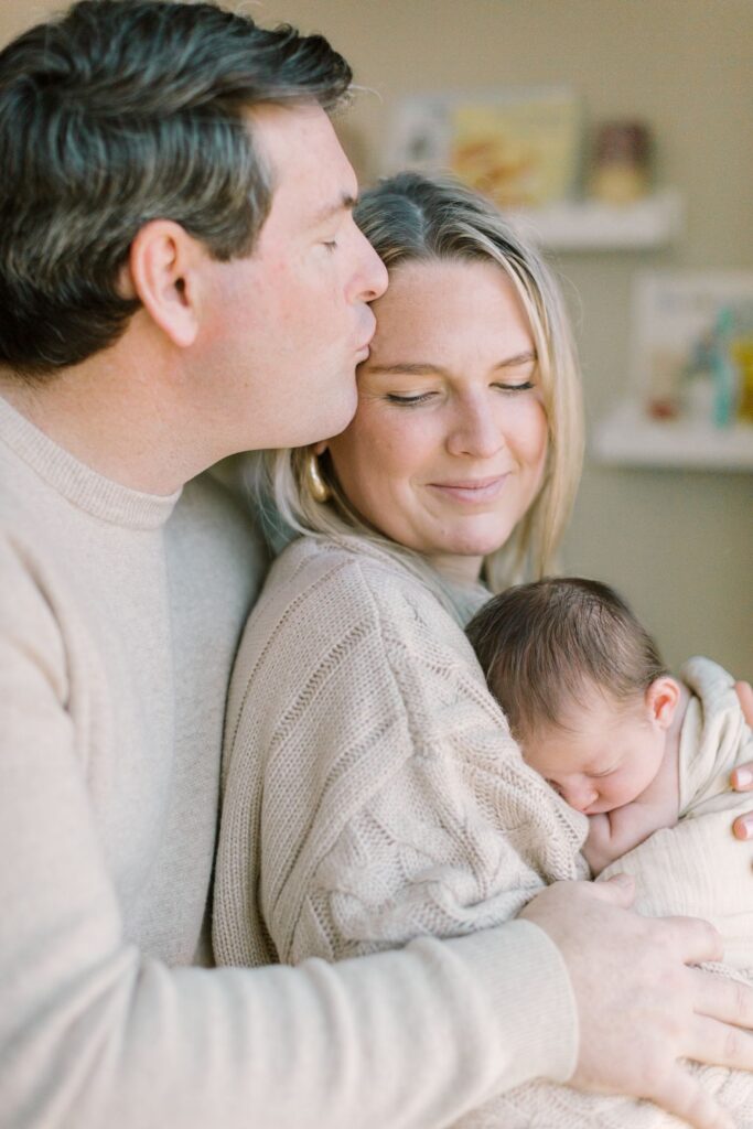 Family cuddling their newborn during an in-home session featured in a newborn photography cost guide by Lindsey Lambert Photography in Raleigh NC.