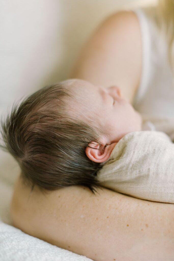 Newborn resting on a parent's arm during a lifestyle session featured in a newborn photography pricing article by Lindsey Lambert Photography.