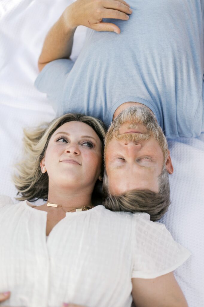 Mom and dad lying together in coordinated summer family photo outfits photographed by Lindsey Lambert Photography in Raleigh NC.