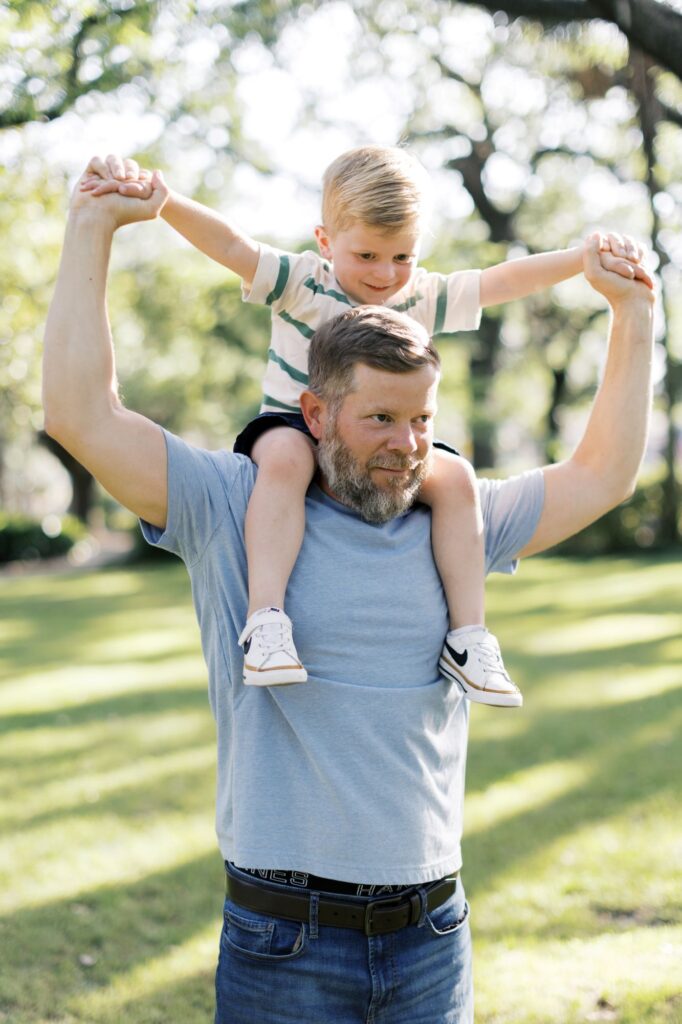 Father carrying son on his shoulders in casual summer family photo outfits photographed by Lindsey Lambert Photography in Raleigh NC.