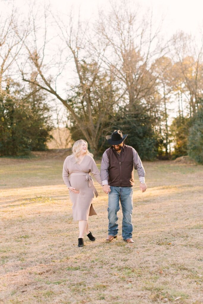 Parents-to-be walking together during golden hour, illustrating the best time to do maternity photos outdoors in Raleigh NC.