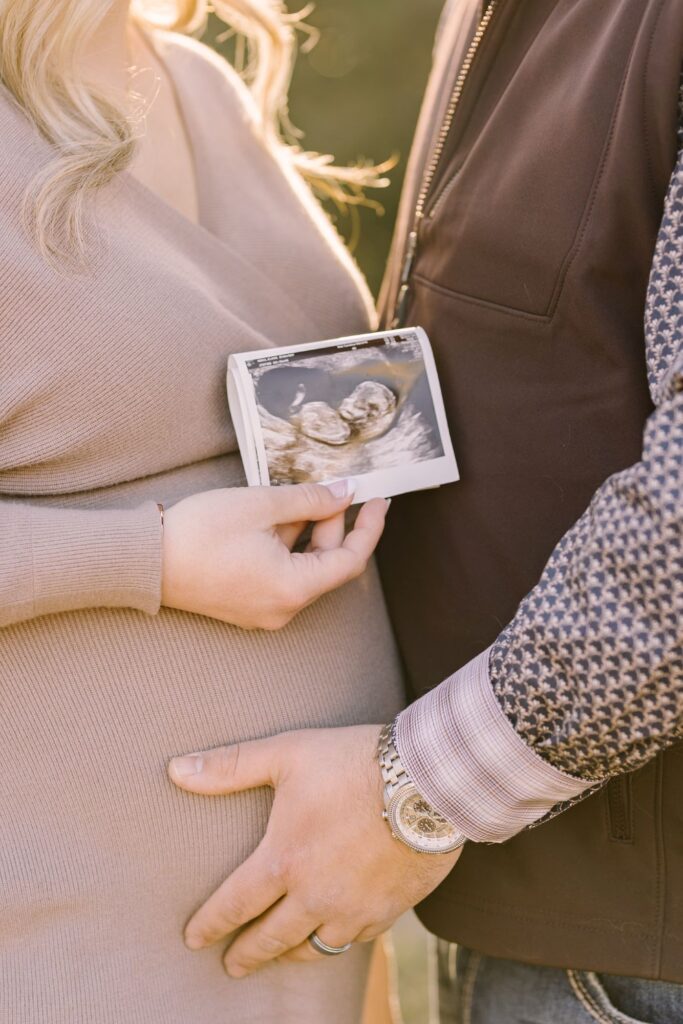 Close-up maternity portrait with ultrasound photo featured in a blog about when to take maternity photos by Lindsey Lambert Photography.