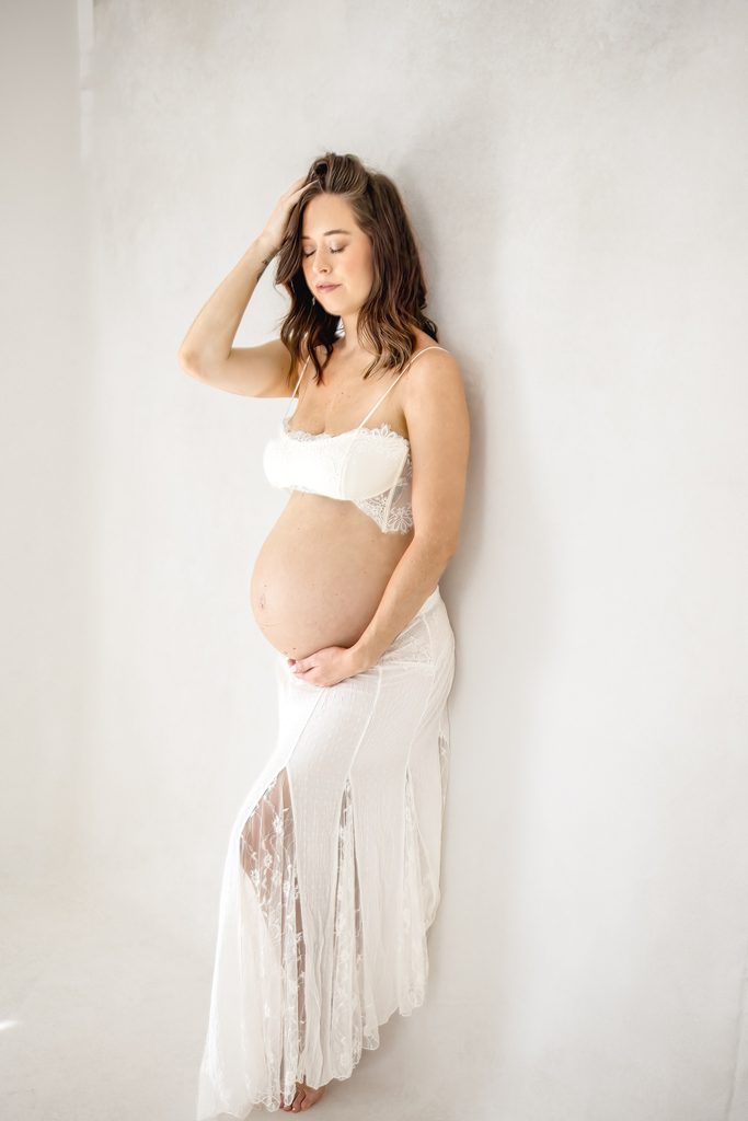Raleigh maternity and newborn photos by Lindsey Lambert Photography featuring an expecting mother in a white two-piece outfit.