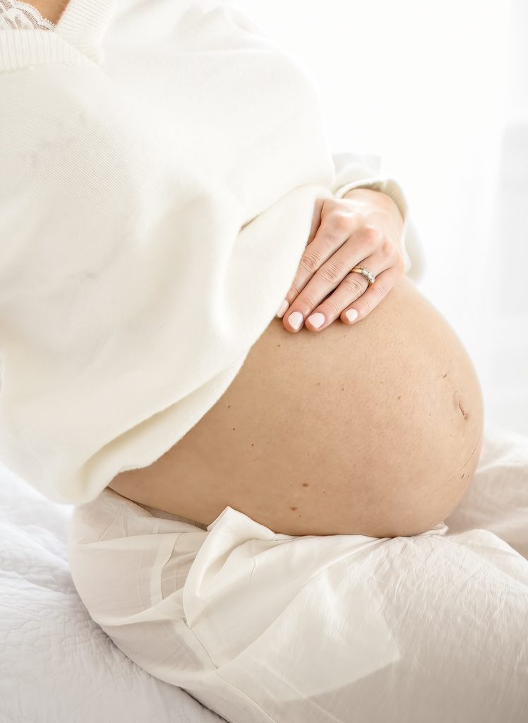 Close-up maternity photo of an expecting mother holding her baby bump by Lindsey Lambert Photography in Raleigh NC.