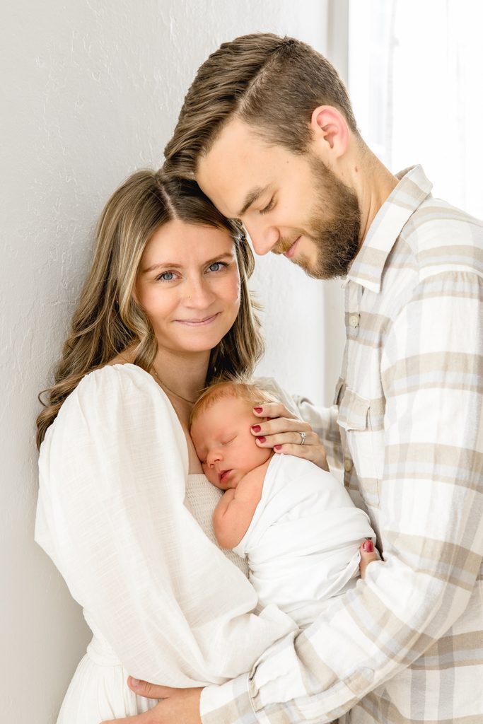 Mom and dad holding their newborn baby during a Raleigh newborn photography session with Lindsey Lambert Photography.