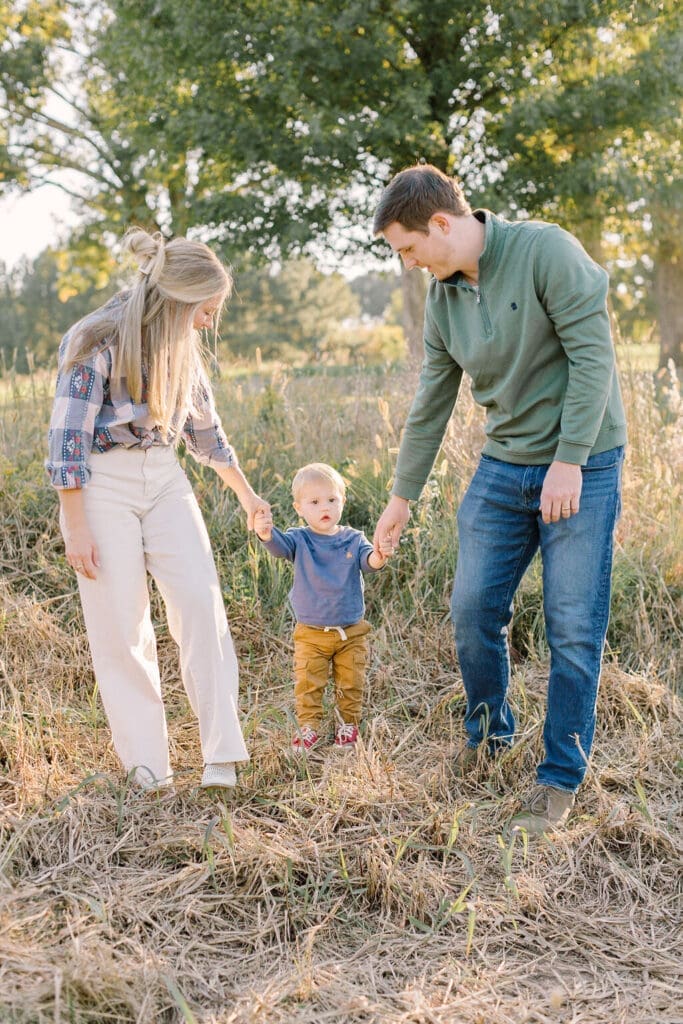 Young family during a Raleigh NC family photography session, walking through a sunlit field holding their toddler’s hands for a warm, natural portrait.
Prepare your Raleigh family photo session. This is a Raleigh Family Photo Style Guide helping you choose colors and clothes.